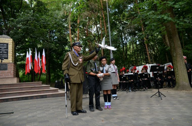 "W hołdzie poległym podczas II wojny światowej" - na zdjęciu widać kombatanta i harcerkę  podczas wypuszczania w niebo białego gołębia