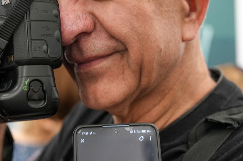 Tadeusz Topolski ze złotym medalem. Na zdjęciu widać zbliżenie na twarz Topolskiego, ma aparat przy oku, przed nim na telefonie wyświetla się medal.