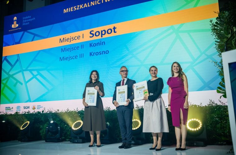 Indeks Zdrowych Miast 2025. Konin drugi w kategorii Mieszkalnictwo. Na zdjęciu trzy osoby, w środku zastępca prezydenta Witold Nowak, odbierają nagrody.