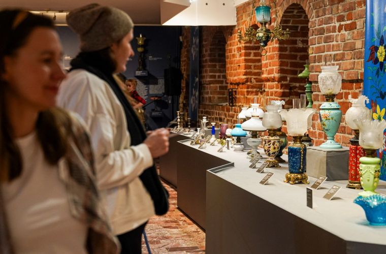 Wystawa świeczników w muzeum. Na zdjęciu widać osobę oglądającą wystawę.