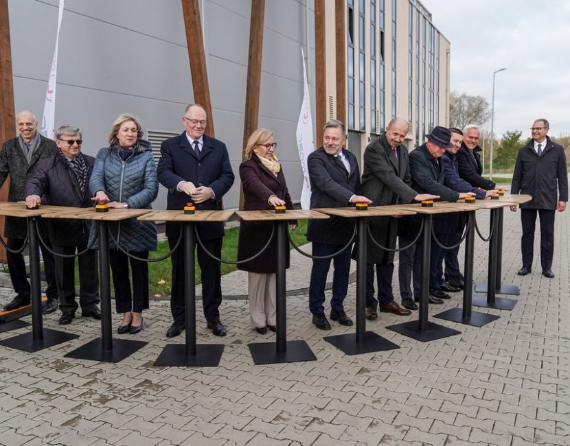 Ciepłownia geotermalna oddana do użytku. Na zdjęciu widać 10 osób stojących za stolikami ze specjalnymi przyciskami do symbolicznego włączenia instalacji.