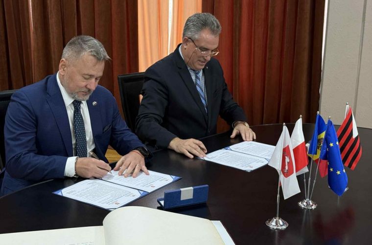 Konin i Ungheni zacieśniają współpracę. Na zdjęciu prezydent Konina i burmistrz Ungheni siedzą za stołem i podpisują umowę.