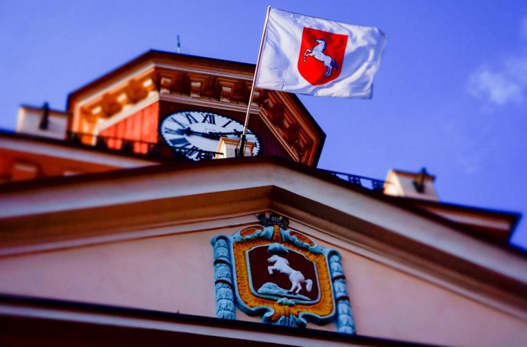 Radni z Poznania za atomem dla Konina. Na zdjęciu jest widoczna wieża ratusza i fragment górnej części budynku z herbem miasta i miejską flagą powiewającą na wietrze.