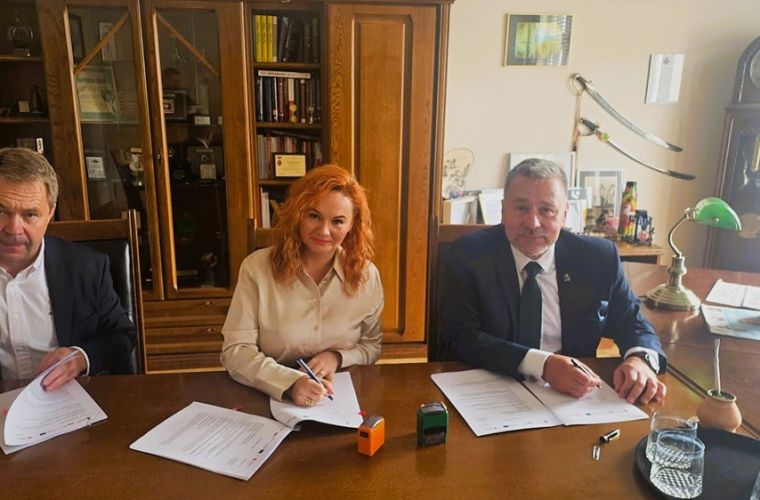 Koniński projekt parasolowy w fazie realizacji. Na zdjęciu za stołem w gabinecie siedzą 3 osoby: szef firmy wykonawcze, skarbnik Konina i prezydent Konina. Podpisują umowę i patrzą w obiektyw.