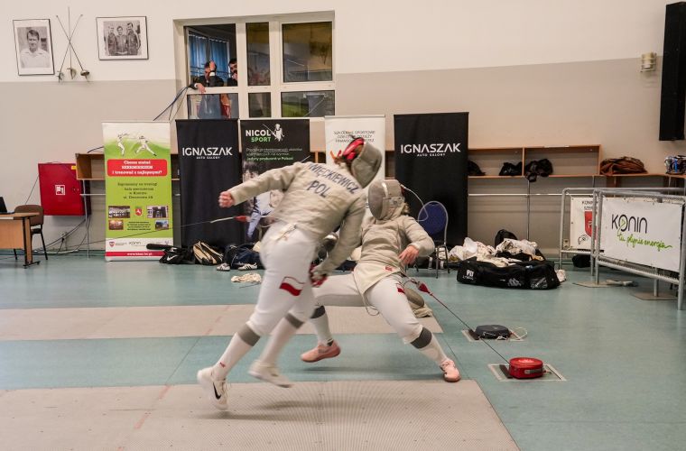 Zdjęcie przedstawia zawodników walczących na planszy podczas Mistrzostw Polski Młodzieżowców w szabli kobiet i mężczyzn