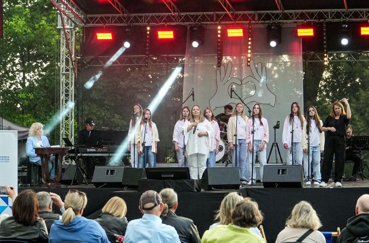 Zdjęcie przedstawia grupę artystów na scenie podczas koncertu na migi "Zobacz jak słyszę"