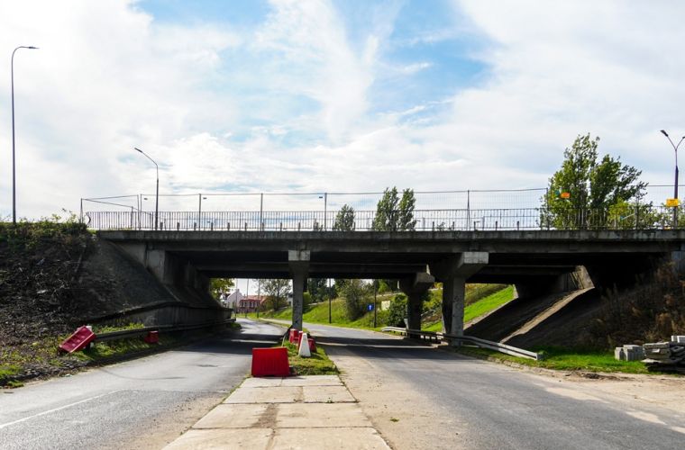 Zniknie stary wiadukt. Na zdjęciu widać  wiadukt z perspektywy, przed nim ustawione prostopadle zapory białe i czerwone na pasie rozdzielającym jezdnię.