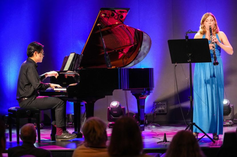 Na zdjęciu widać mężczyznę siedzącego za fortepianem oraz śpiewającą kobietę podczas koncertu koncert muzyki klasycznej poświęcony twórczości Witolda Friemanna