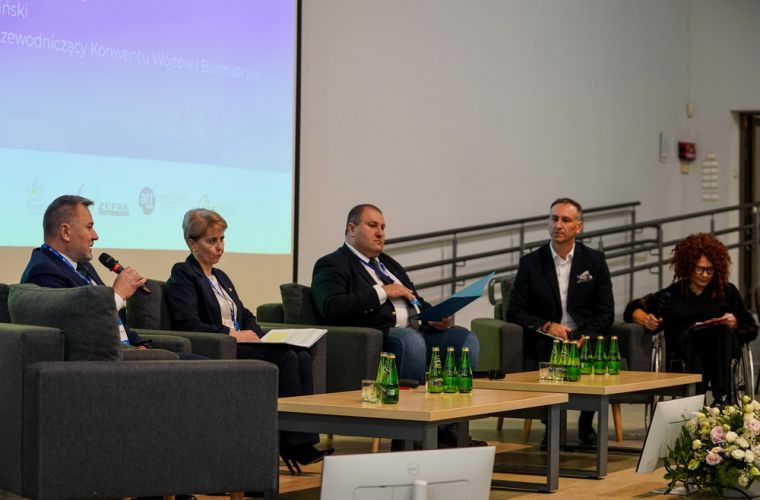 Konin walczy o atom. Widać na zdjęciu uczestników dyskusji siedzących w półkolu na scenie ANS, prezydent Piotr Korytkowski trzyma w ręce mikrofon i jest w trakcie wypowiedzi.