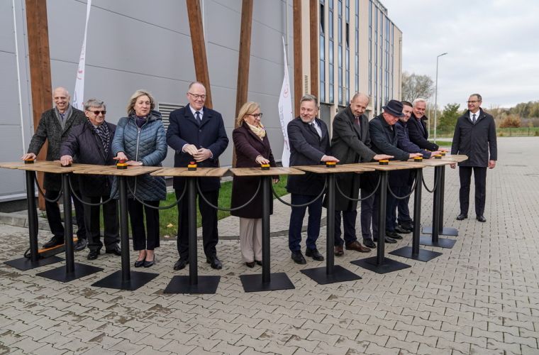 Ciepłownia geotermalna oddana do użytku. Na zdjęciu widać 10 osób stojących za stolikami ze specjalnymi przyciskami do symbolicznego włączenia instalacji.