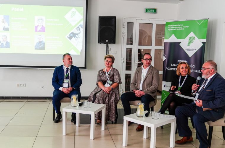 Współpraca kluczem do przyszłości. I Forum Samorządności Aglomeracji Konińskiej. Na zdjęciu widać pięcioro prelegentów podczas dyskusji, siedzących w półkolu, na tle bannera Aglomeracji Konińskiej