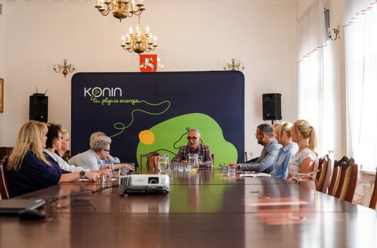 Konin testuje Scholario. Na zdjęciu widać nauczycieli, z-ca prezydenta i szefa firmy Mentalio siedzących przy stole i rozmawiających.