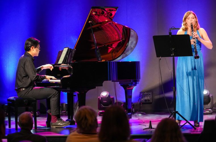 Na zdjęciu widać mężczyznę siedzącego za fortepianem oraz śpiewającą kobietę podczas koncertu koncert muzyki klasycznej poświęcony twórczości Witolda Friemanna