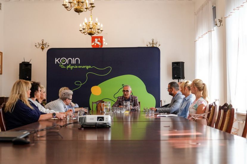 Konin testuje Scholario. Na zdjęciu widać nauczycieli, z-ca prezydenta i szefa firmy Mentalio siedzących przy stole i rozmawiających.