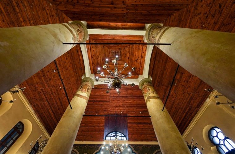 Centrum Czterech Kultur w konińskiej synagodze. Na zdjęciu widać drewniane sklepienie sufitu w środku synagogi wraz z filarami i żyrandolem.