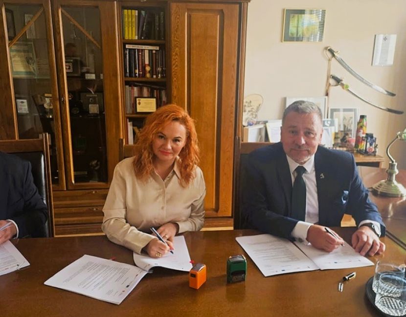 Koniński projekt parasolowy w fazie realizacji. Na zdjęciu za stołem w gabinecie siedzą 3 osoby: szef firmy wykonawcze, skarbnik Konina i prezydent Konina. Podpisują umowę i patrzą w obiektyw.
