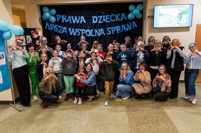 Dziecko w centrum uwagi! Na zdjęciu widać dzieci i dorosłych składających dłonie w kształt serca.