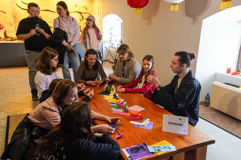 Na zdjęciu widoczna grupa ludzi przy stole do origami podczas Japońskiego pikniku w Muzeum