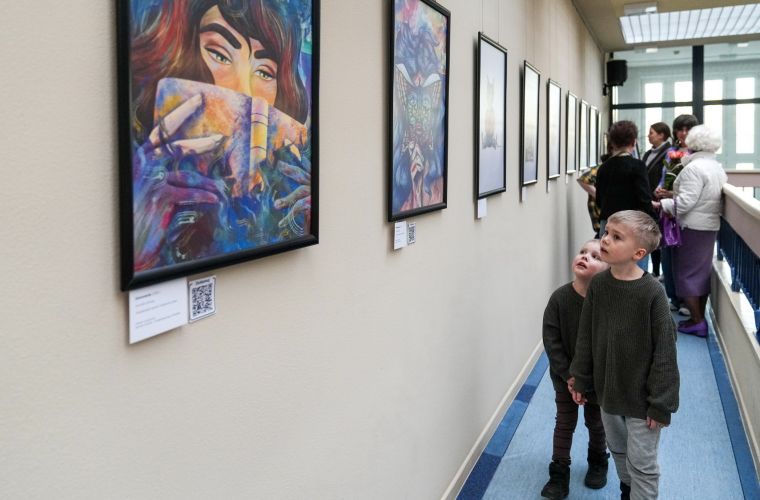 Zdjęcie przedstawia dwóch chłopców oglądających prace na wystawie Magdaleny Jakubowskiej w bibliotece