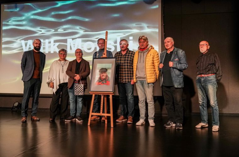 Filmowa opowieść Kazimierza Sochackiego. Na zdjęciu widać grupę osób na scenie, a przed nimi plakat zapowiadający wydarzenie ze zdjęciem pana Sochackiego.