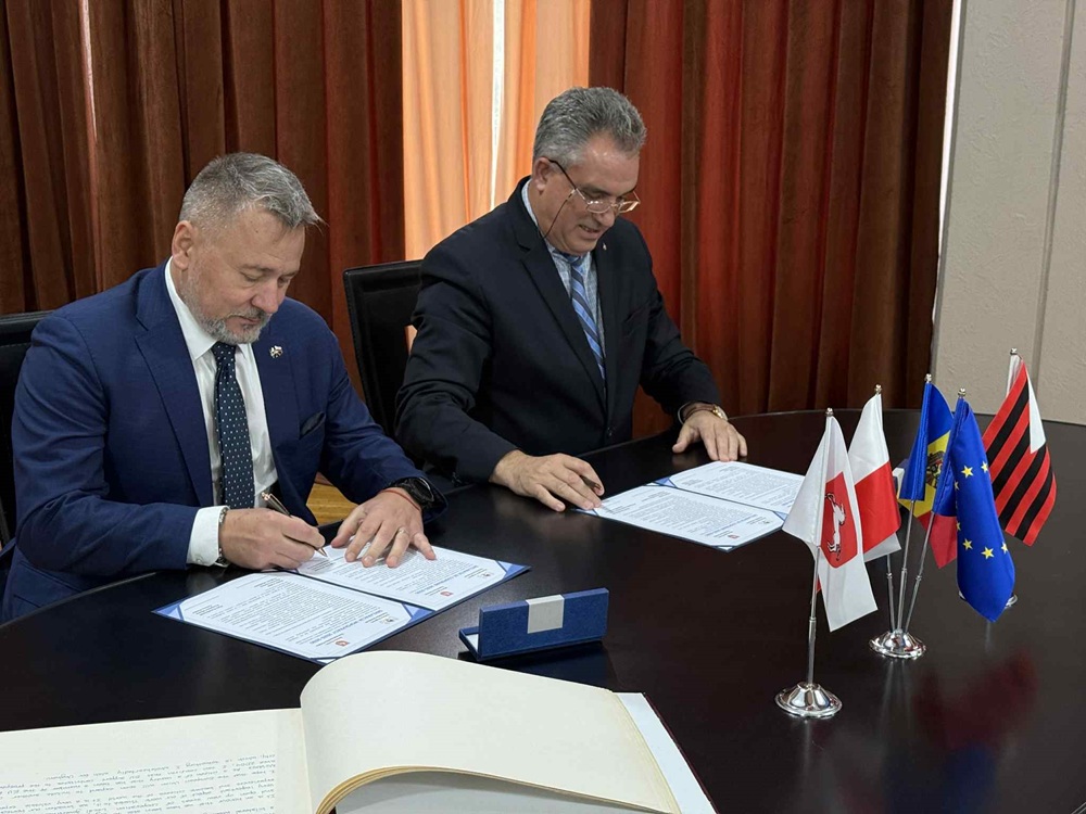 Konin i Ungheni zacieśniają współpracę. Na zdjęciu prezydent Konina i burmistrz Ungheni siedzą za stołem i podpisują umowę.