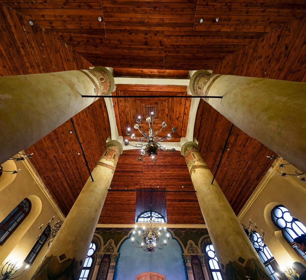 Centrum Czterech Kultur w konińskiej synagodze. Na zdjęciu widać drewniane sklepienie sufitu w środku synagogi wraz z filarami i żyrandolem.