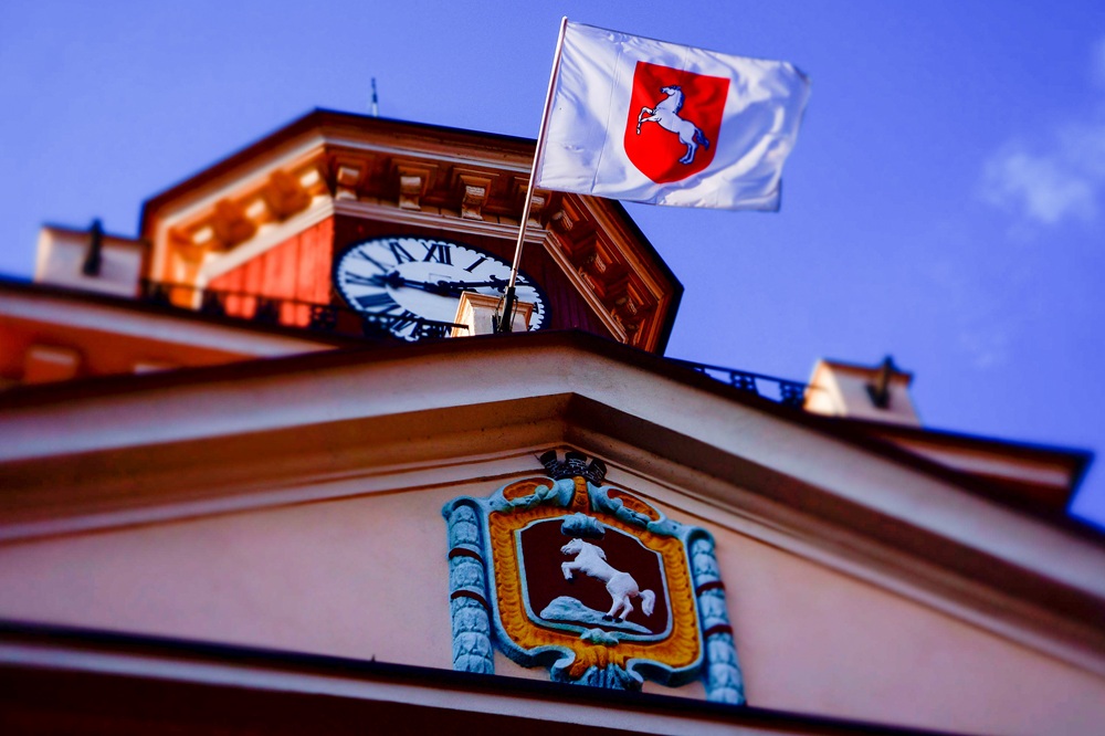 Radni z Poznania za atomem dla Konina. Na zdjęciu jest widoczna wieża ratusza i fragment górnej części budynku z herbem miasta i miejską flagą powiewającą na wietrze.