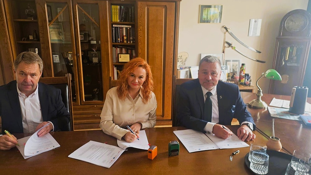 Koniński projekt parasolowy w fazie realizacji. Na zdjęciu za stołem w gabinecie siedzą 3 osoby: szef firmy wykonawcze, skarbnik Konina i prezydent Konina. Podpisują umowę i patrzą w obiektyw.