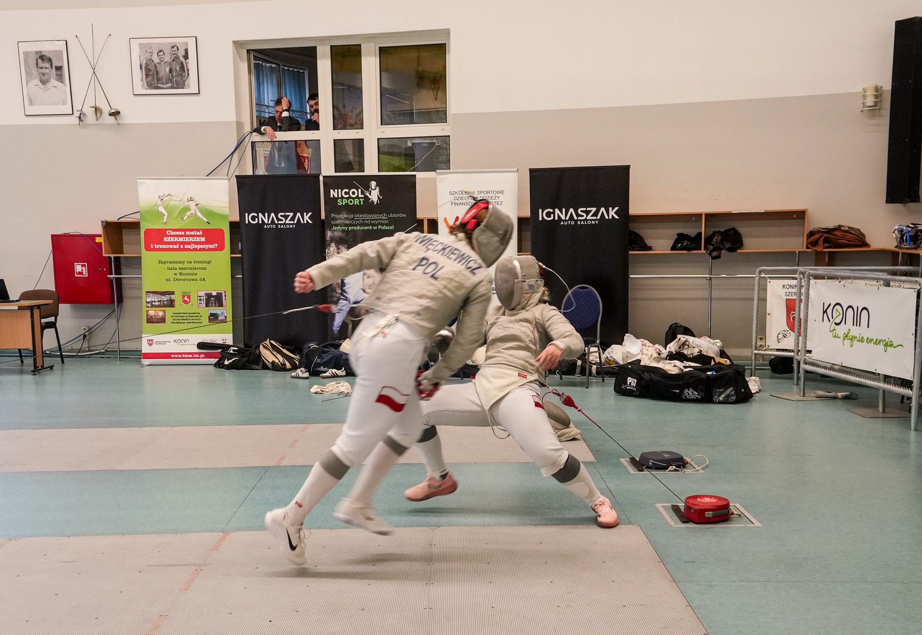 Zdjęcie przedstawia zawodników walczących na planszy podczas Mistrzostw Polski Młodzieżowców w szabli kobiet i mężczyzn