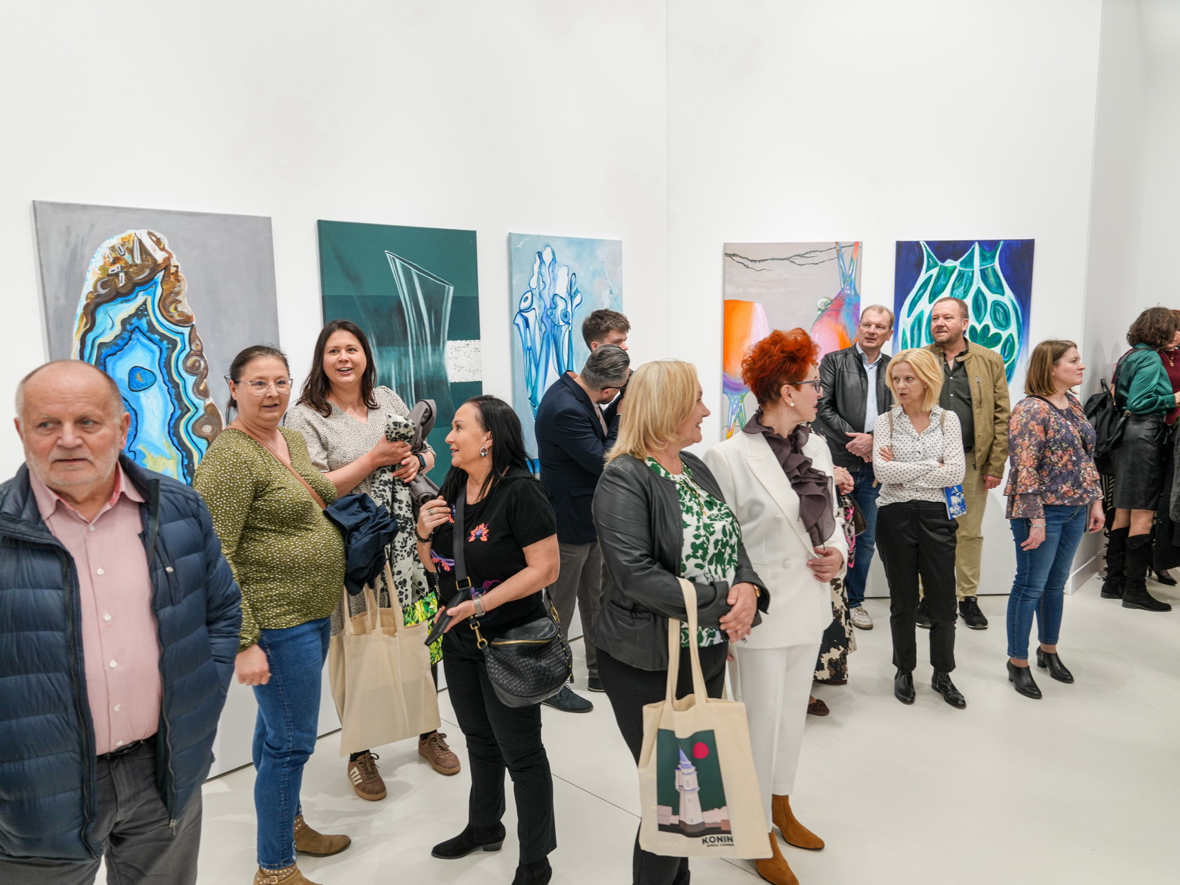 Zdjęcie przedstawia uczestników wernisażu wystawy zatytułowanej „Ciała krystaliczne”