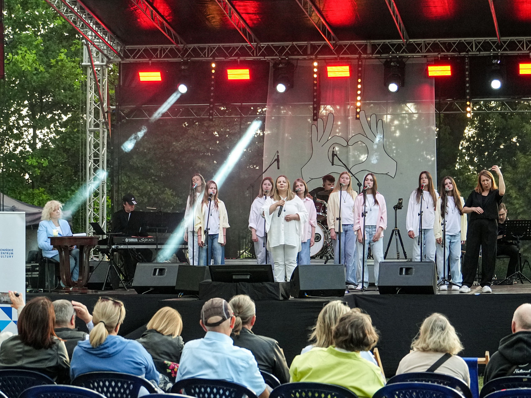 Zdjęcie przedstawia grupę artystów na scenie podczas koncertu na migi "Zobacz jak słyszę"